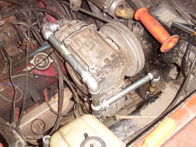Metal piping T-s forward to the front bumper air tank, with a short hose section going straight down - far from the compressor o